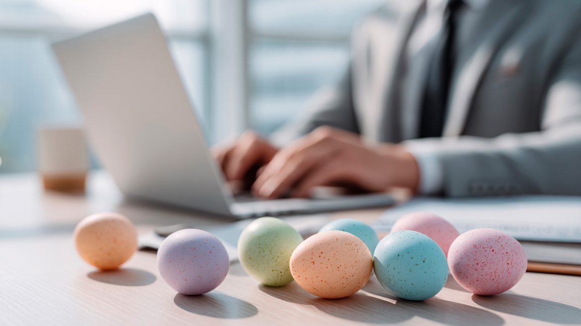 Ostereier liegen auf dem Schreibtisch. Dahinter ein Mann mit Laptop, dessen Gesicht man nicht sieht.