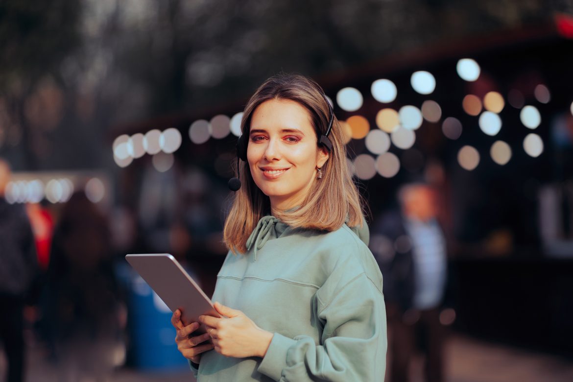 Eine Frau mit Tablet in der Hand steht in einer Veranstaltungshalle.