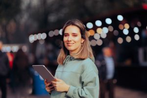 Eine Frau mit Tablet in der Hand steht in einer Veranstaltungshalle.