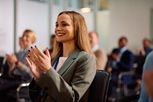 Eine glückliche Business Woman klatscht in einer Menschenmenge.